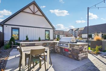 a patio with a grill and a table and chairs at Premier at West Park Luxury Apartment Homes, Greeley, CO